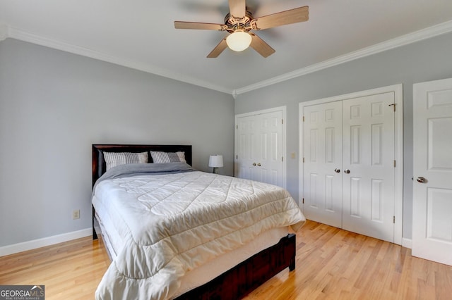 bedroom featuring multiple closets, crown molding, light wood-style floors, baseboards, and a ceiling fan