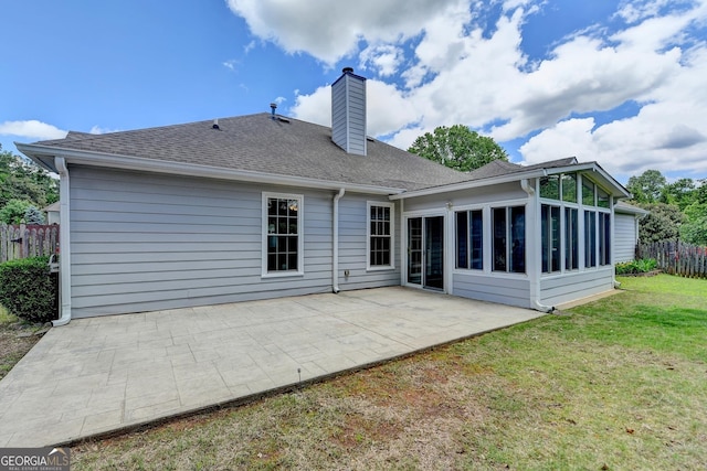 rear view of property featuring a chimney, a patio area, a shingled roof, and a sunroom