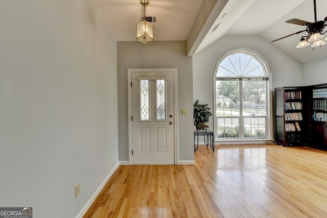 foyer entrance featuring a ceiling fan, lofted ceiling, light wood finished floors, baseboards, and a chandelier