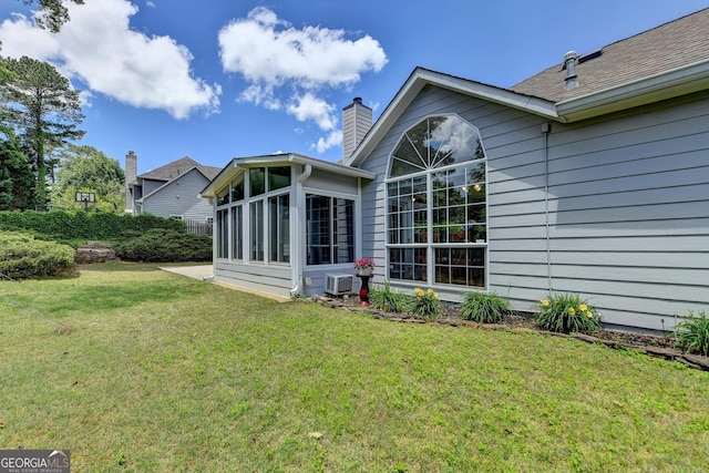 back of house featuring a sunroom, a yard, a chimney, and central air condition unit