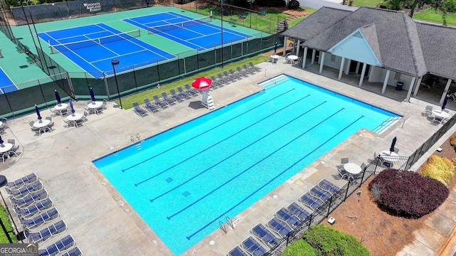 community pool with fence, a patio area, and a tennis court