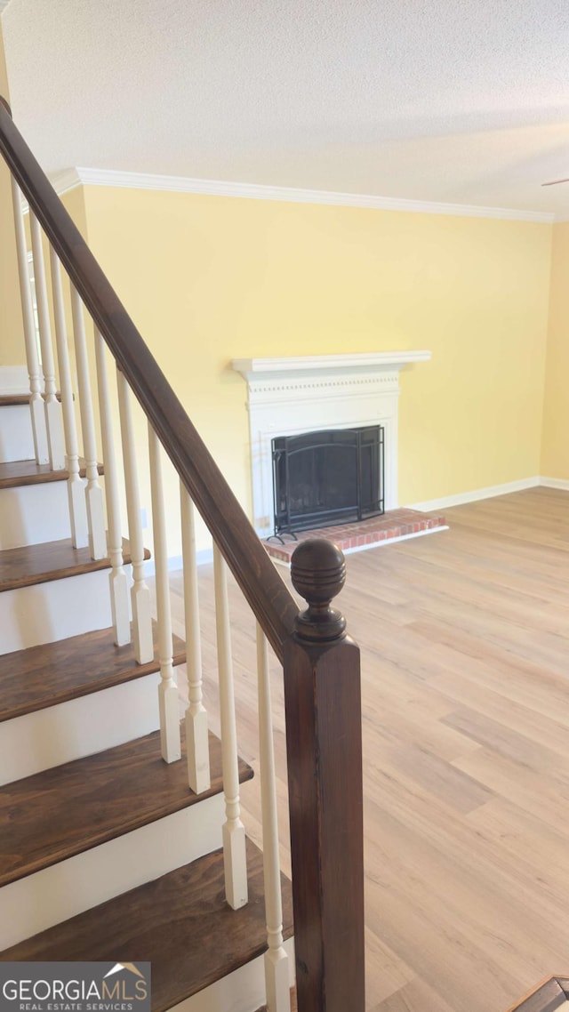 138 Tamara Ct, Athens, GA 30606 - stairway with crown molding, wood finished floors, a fireplace with raised hearth, baseboards, and a textured ceiling