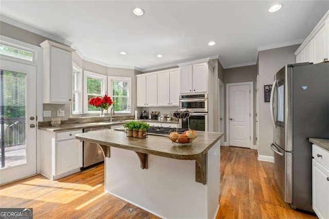 3705 Rolling Creek Dr, Buford, GA 30519 - kitchen featuring appliances with stainless steel finishes, ornamental molding, white cabinets, a kitchen island, and light wood finished floors