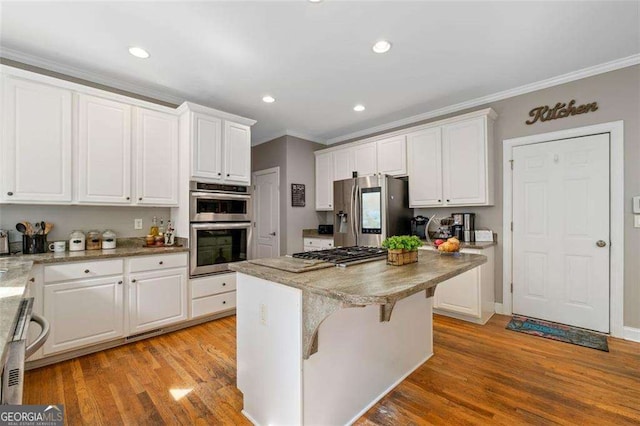 3705 Rolling Creek Dr, Buford, GA 30519 - kitchen with stainless steel appliances, ornamental molding, white cabinets, a kitchen island, and light wood-style flooring