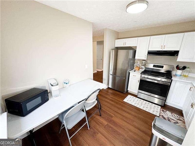 6092 Leverett Dr, Lithonia, GA 30038 - kitchen featuring stainless steel appliances, under cabinet range hood, light countertops, white cabinets, and dark wood-style flooring