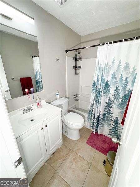 6092 Leverett Dr, Lithonia, GA 30038 - bathroom featuring tile patterned flooring, vanity, shower / tub combo with curtain, toilet, and a textured ceiling