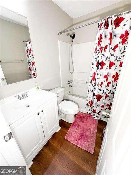 6092 Leverett Dr, Lithonia, GA 30038 - full bath featuring wood finished floors, shower / tub combo with curtain, toilet, and vanity