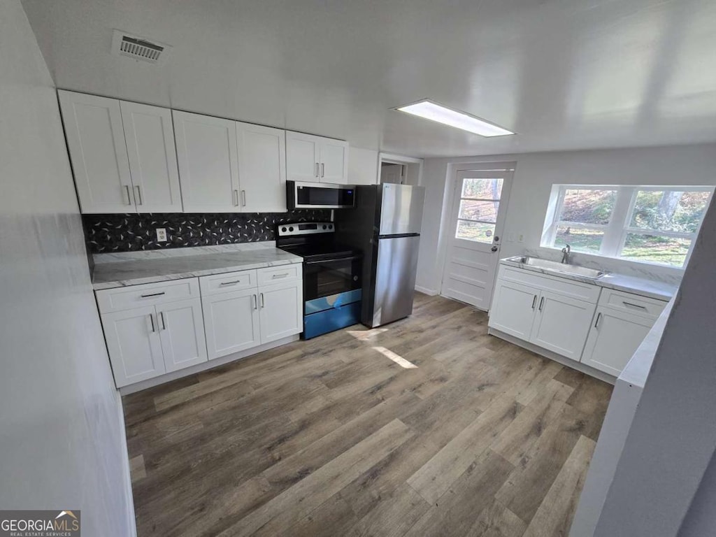 507 Jefferson Hwy, Winder, GA 30680 - kitchen featuring appliances with stainless steel finishes, a sink, white cabinetry, light wood-type flooring, and backsplash