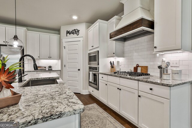 kitchen with stainless steel appliances, custom exhaust hood, a sink, white cabinets, and recessed lighting