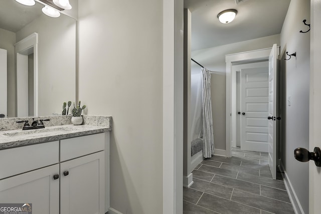 full bath featuring vanity and baseboards