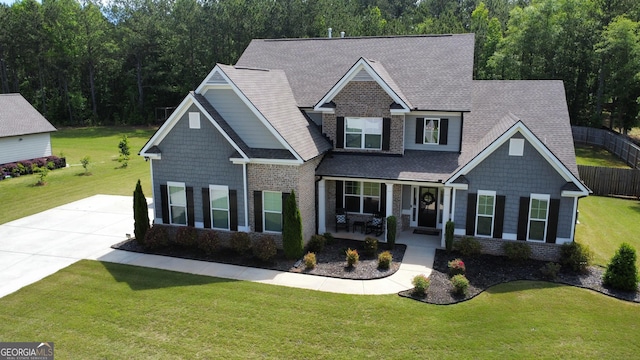 craftsman house featuring covered porch, roof with shingles, driveway, and brick siding