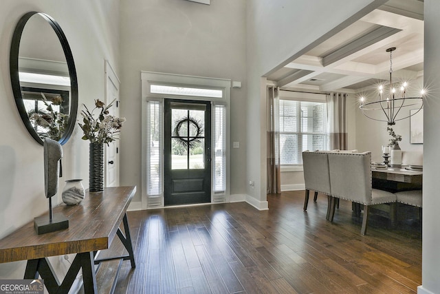 entryway with a chandelier, coffered ceiling, dark wood finished floors, beamed ceiling, and baseboards