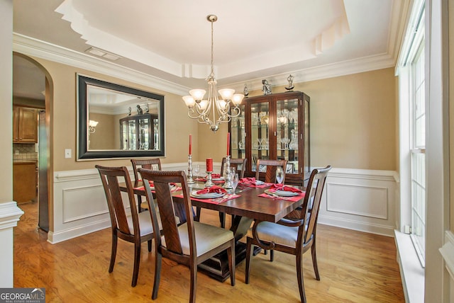 4765 Smokestone Dr, Douglasville, GA 30135 - dining area featuring a tray ceiling, light wood-style flooring, arched walkways, a wainscoted wall, and ornamental molding