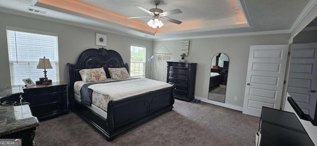 bedroom featuring a tray ceiling, carpet, baseboards, ceiling fan, and ornamental molding