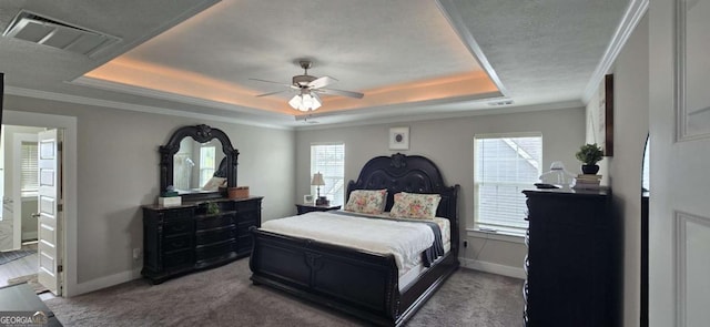 carpeted bedroom featuring a tray ceiling, baseboards, ornamental molding, and a ceiling fan