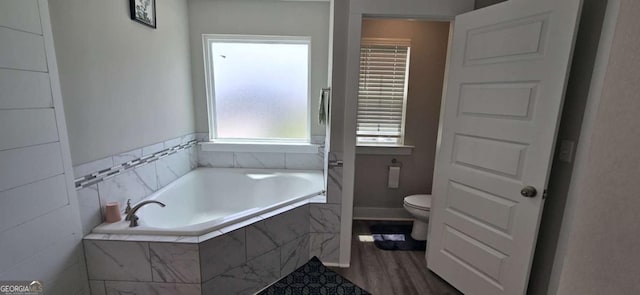 bathroom featuring a garden tub, toilet, and wood finished floors