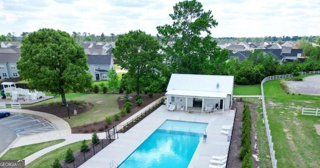 community pool with an outbuilding, a storage structure, a residential view, and a patio