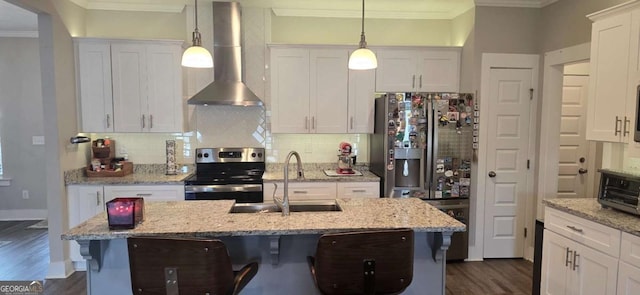 kitchen featuring stainless steel appliances, wall chimney range hood, a sink, crown molding, and dark wood finished floors