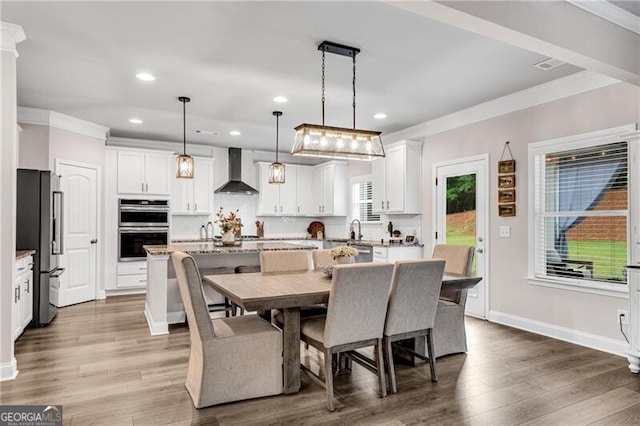 dining area with crown molding, wood finished floors, recessed lighting, and baseboards