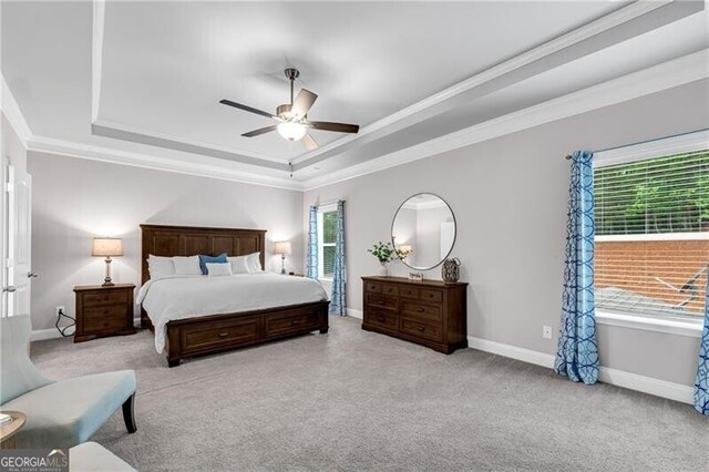 carpeted bedroom featuring a raised ceiling, crown molding, baseboards, and a ceiling fan