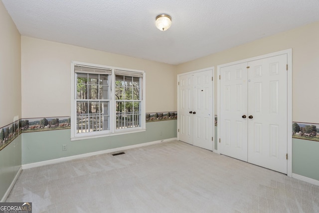 5695 Sweetbriar Trl, Macon, GA 31210 - unfurnished bedroom with carpet flooring, baseboards, two closets, and a textured ceiling