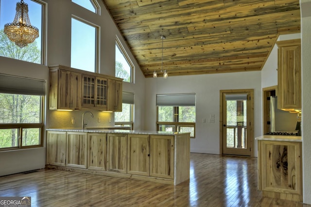 kitchen with wood ceiling, high vaulted ceiling, hardwood / wood-style floors, a peninsula, and glass insert cabinets