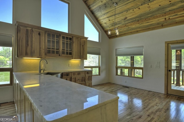 kitchen featuring a sink, high vaulted ceiling, glass insert cabinets, light wood-style flooring, and wood ceiling