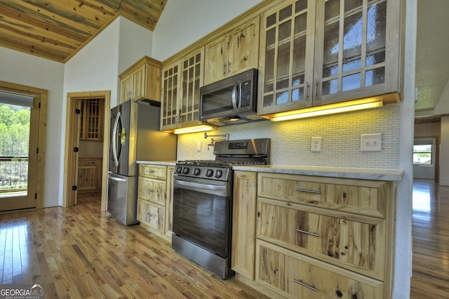 kitchen with stainless steel appliances, lofted ceiling, light wood-style floors, tasteful backsplash, and light countertops
