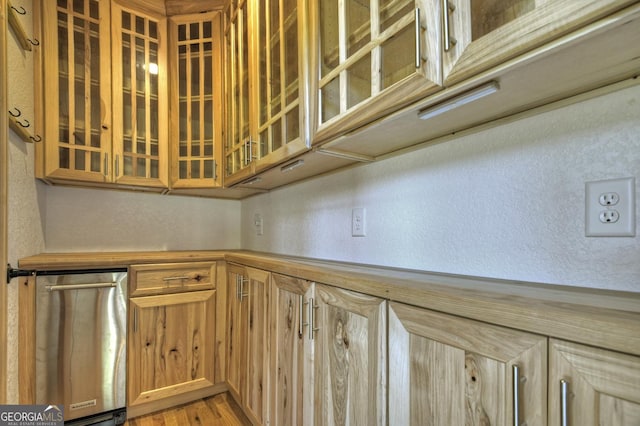 kitchen featuring a textured wall, glass insert cabinets, and light wood finished floors