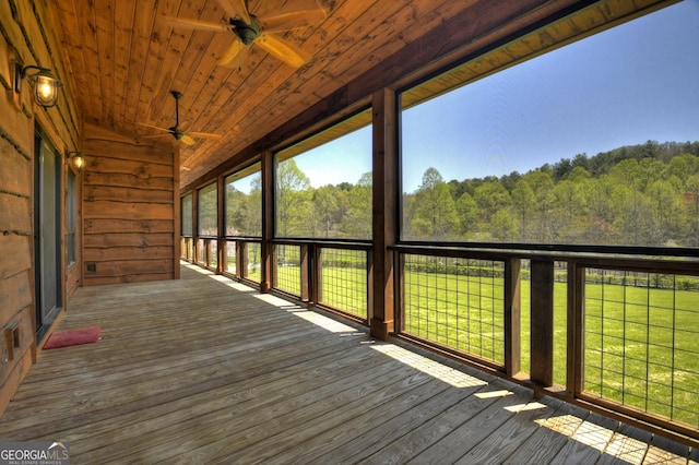 wooden deck featuring ceiling fan and a view of trees