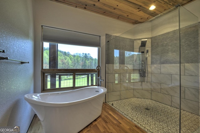 full bath featuring wood finished floors, a shower stall, a freestanding bath, and wood ceiling