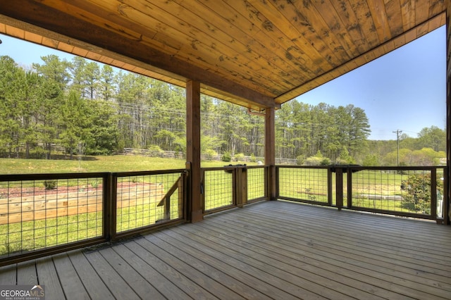 deck featuring view of wooded area and a yard