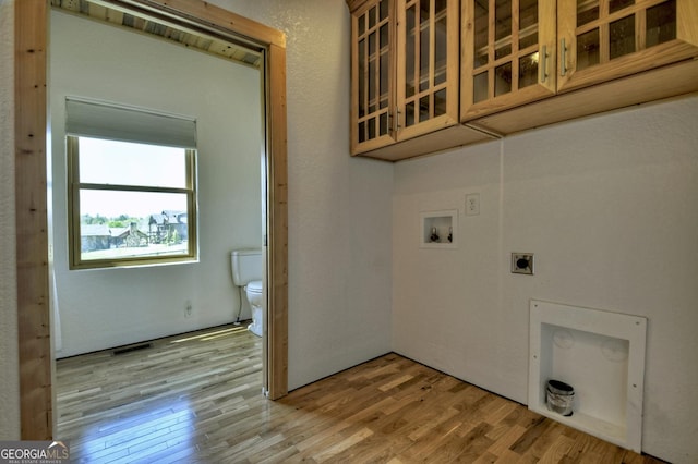 clothes washing area with light wood-style flooring, hookup for an electric dryer, washer hookup, and cabinet space