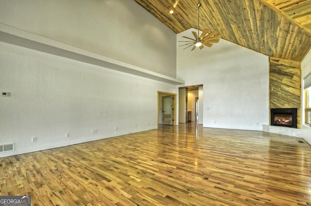 unfurnished living room featuring wood finished floors, high vaulted ceiling, wood ceiling, ceiling fan, and a fireplace