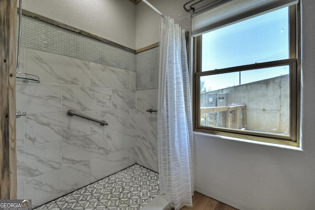 full bathroom featuring tiled shower and wood finished floors
