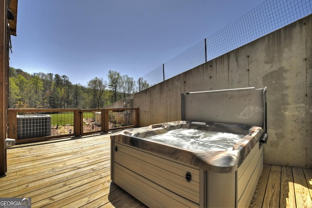 wooden deck with a hot tub and central AC