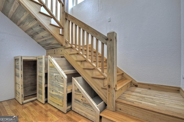 stairway with a textured wall and wood finished floors