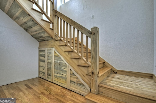 stairway with a textured wall and wood finished floors