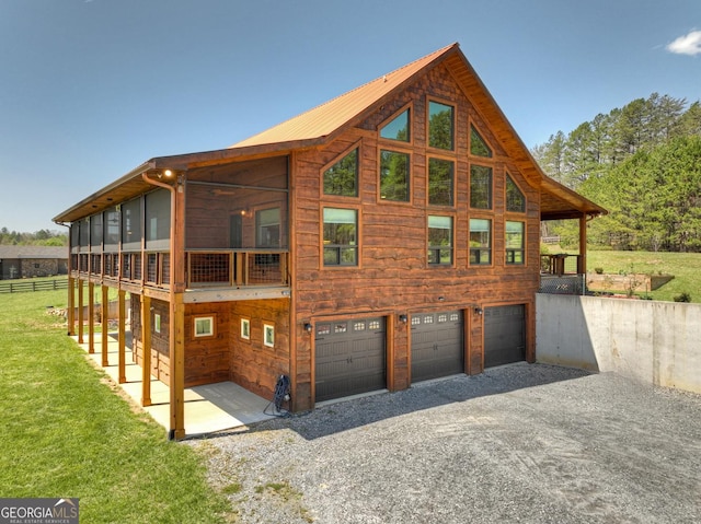 back of property with a garage, gravel driveway, and a lawn