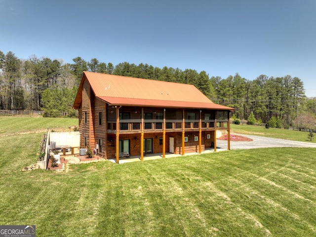 back of house featuring a patio, a lawn, metal roof, and a wooden deck