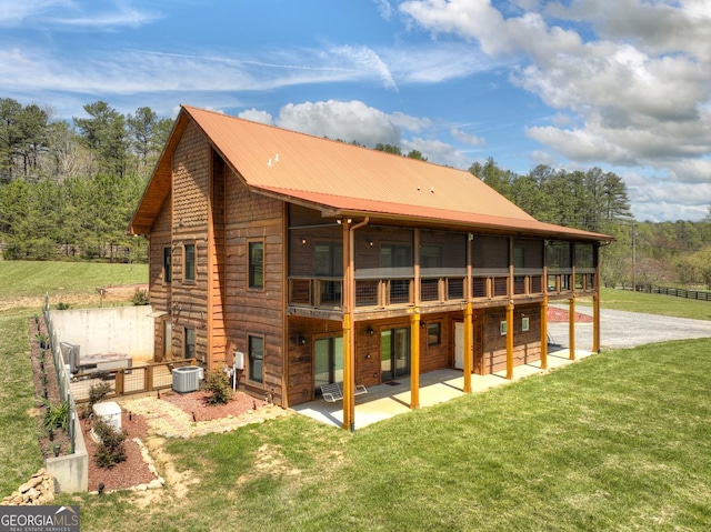 back of property featuring a patio, a lawn, and metal roof
