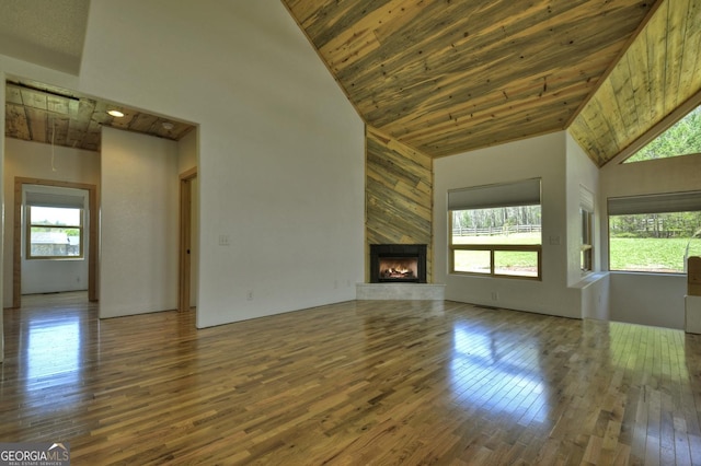 unfurnished living room featuring high vaulted ceiling, wood ceiling, wood-type flooring, and a premium fireplace