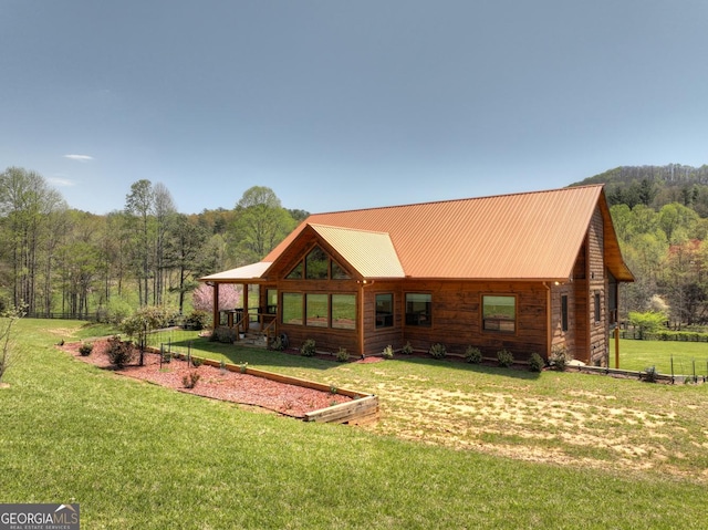 rear view of house with a yard, a view of trees, and metal roof