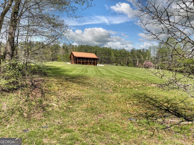 view of green lawn with an outbuilding and a view of trees