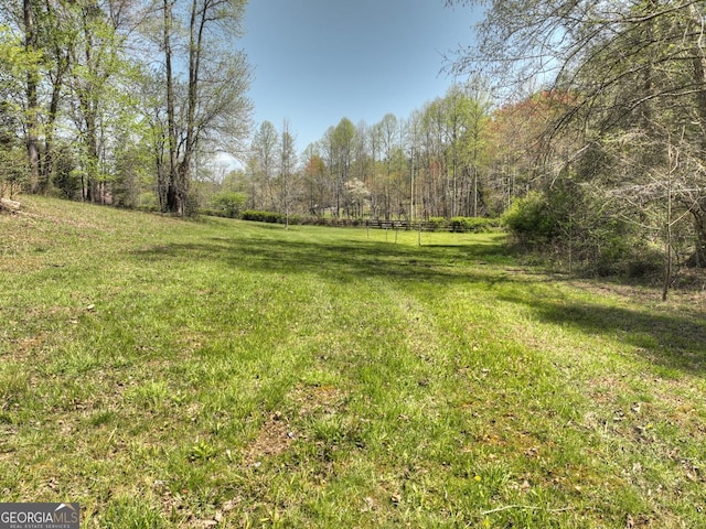 view of grassy yard with a view of trees