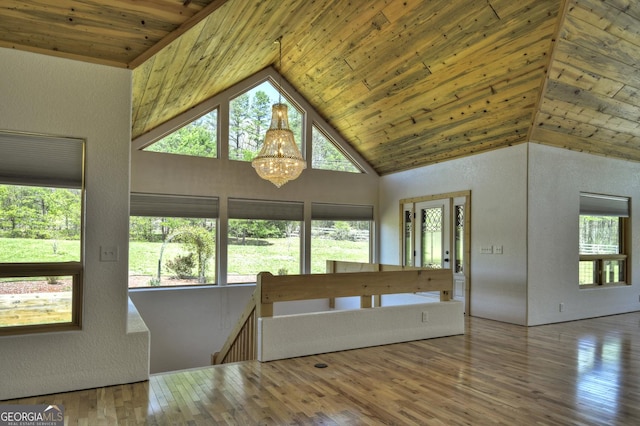 unfurnished living room featuring wooden ceiling, plenty of natural light, a chandelier, hardwood / wood-style flooring, and high vaulted ceiling