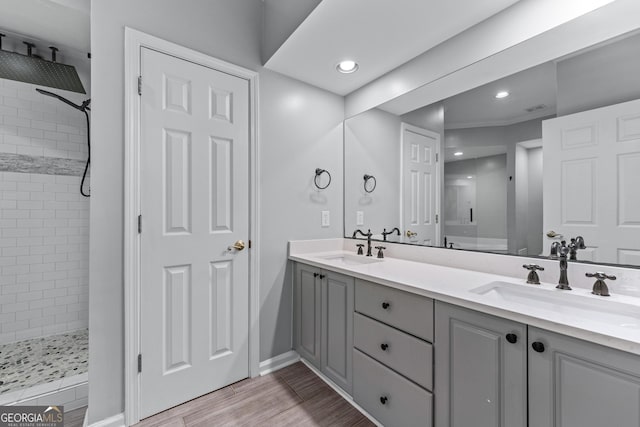 3636 Habersham Rd NW Unit 2101, Atlanta, GA 30305 - bathroom featuring double vanity, a tile shower, baseboards, recessed lighting, and wood finished floors