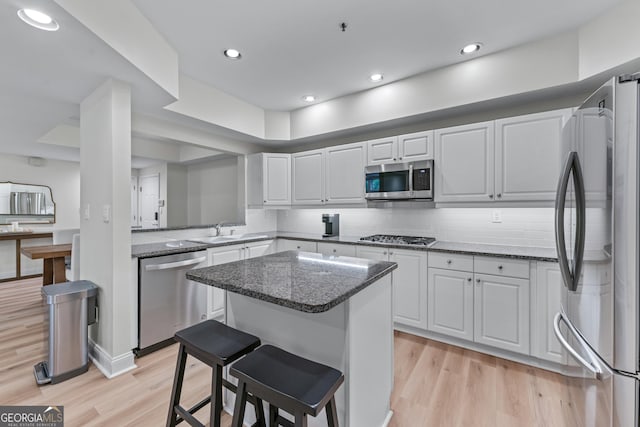 3636 Habersham Rd NW Unit 2101, Atlanta, GA 30305 - kitchen featuring appliances with stainless steel finishes, a sink, a kitchen island, light wood finished floors, and a breakfast bar