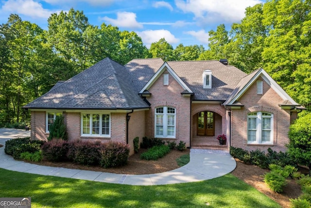 view of front of house featuring brick siding, a front lawn, and a shingled roof