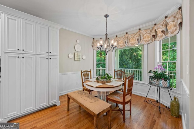 dining area with light wood finished floors, a chandelier, plenty of natural light, ornamental molding, and baseboards